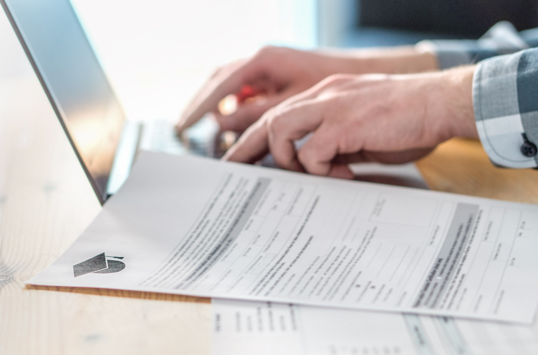 Person using laptop with financial form nearby